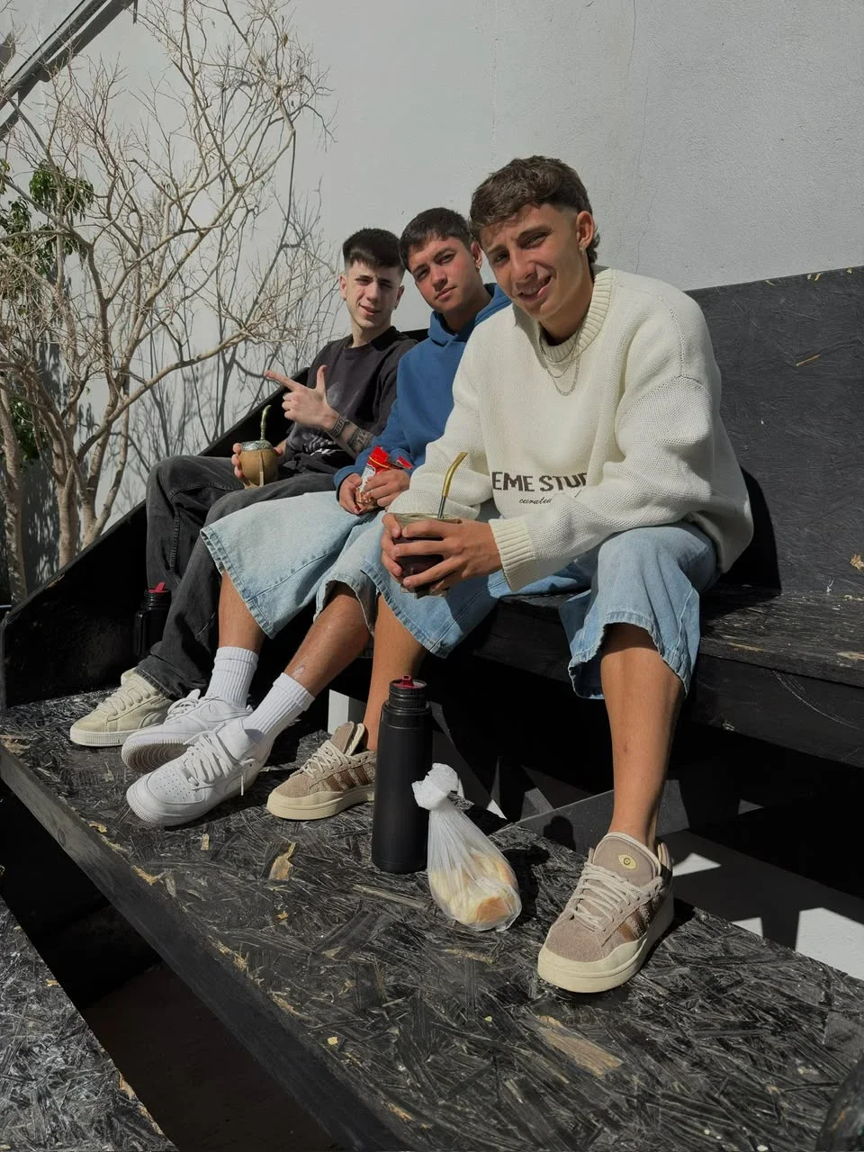 Tres amigos jóvenes tomando mate juntos al sol